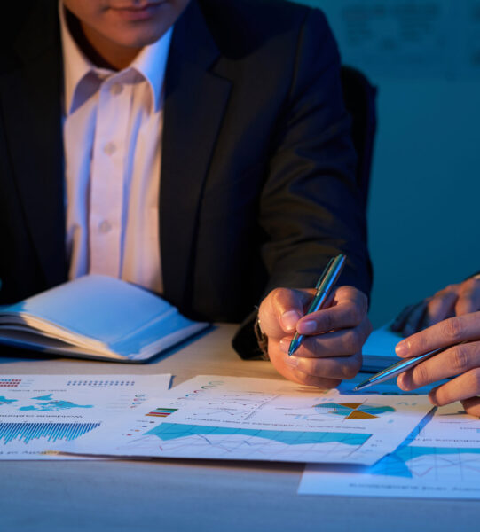 Close-up image of coworkers discussing financial charts at business meeting